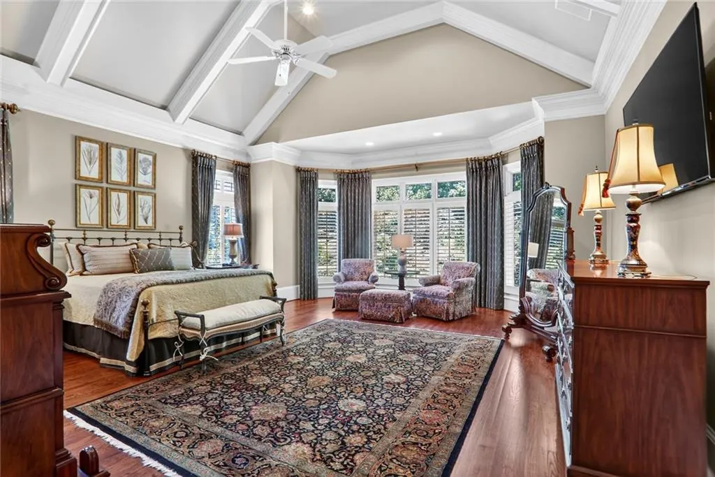 Bedroom with high vaulted ceiling, multiple windows, ceiling fan, dark wood finished floors, and crown molding
