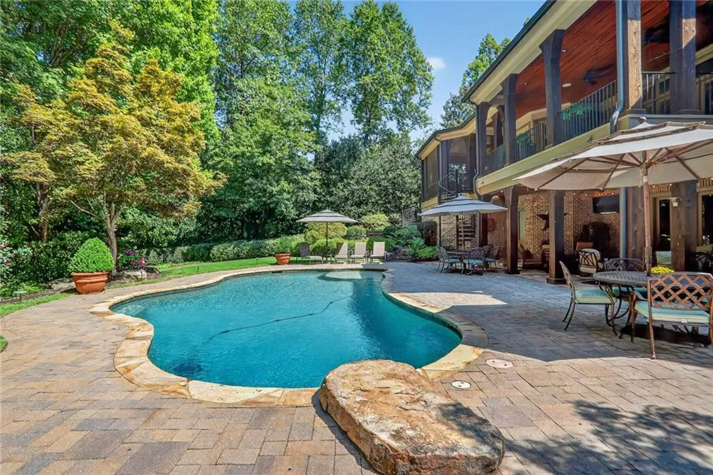 Outdoor pool with a patio, a sunroom, a balcony, and outdoor dining area