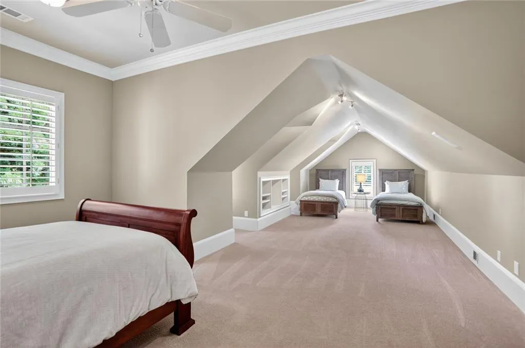 Bedroom with a ceiling fan, light colored carpet, ornamental molding, and vaulted ceiling