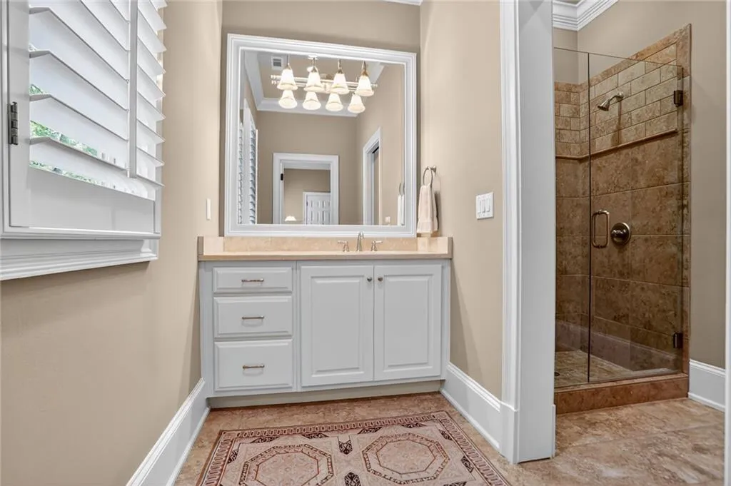 Bathroom featuring a stall shower, vanity, and ornamental molding