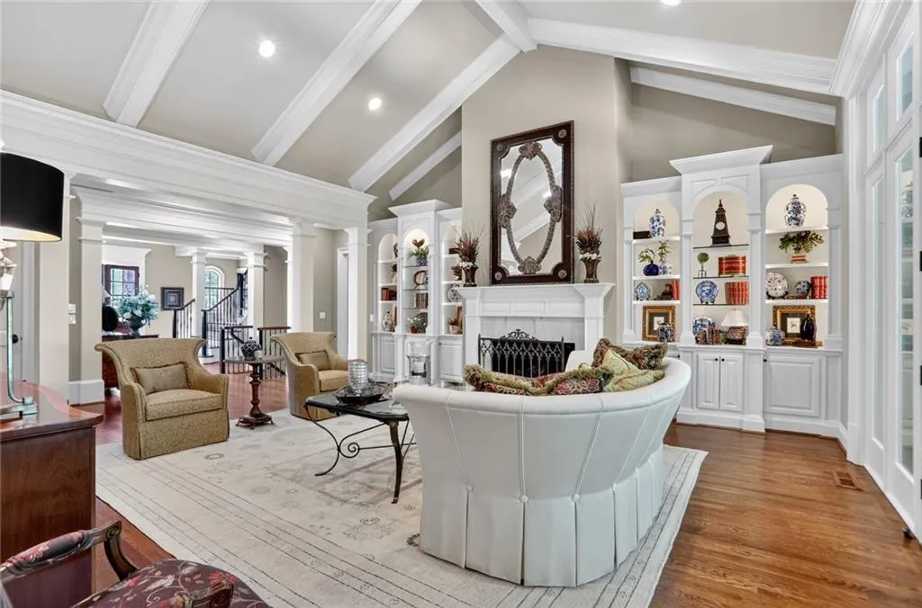 Living room with decorative columns, a fireplace, beamed ceiling, high vaulted ceiling, and wood finished floors