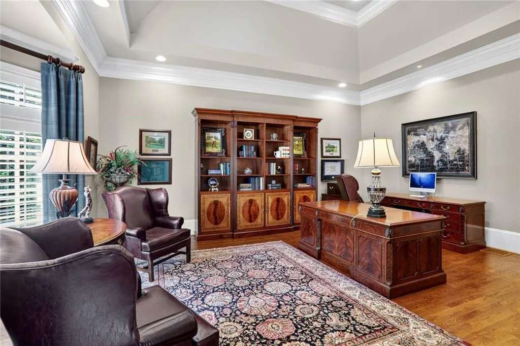 Home office featuring light wood-style floors, ornamental molding, recessed lighting, and a tray ceiling