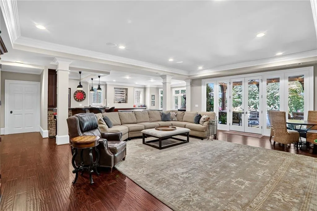 Living room featuring ornate columns, ornamental molding, dark wood-style flooring, french doors, and recessed lighting