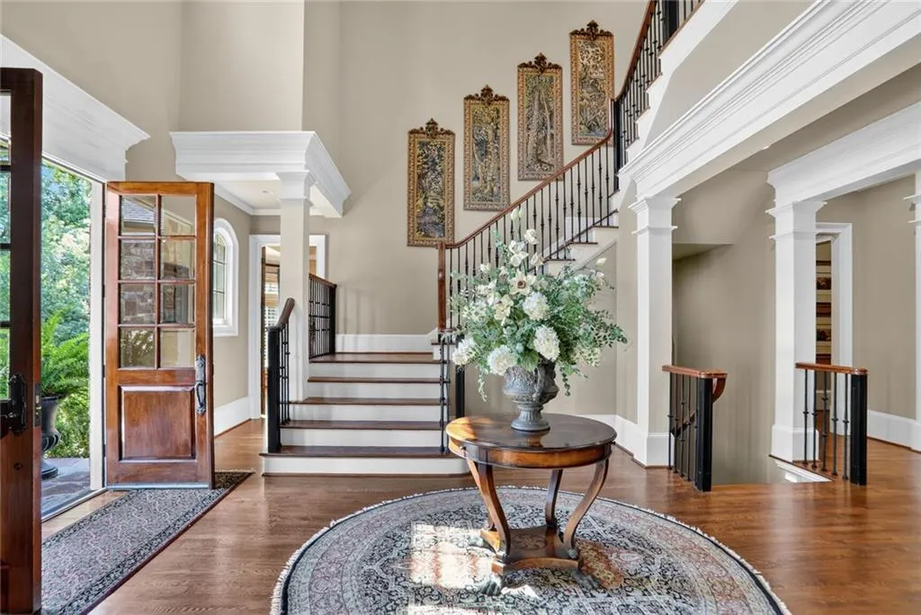Entryway with stairs, wood finished floors, a towering ceiling, and ornate columns