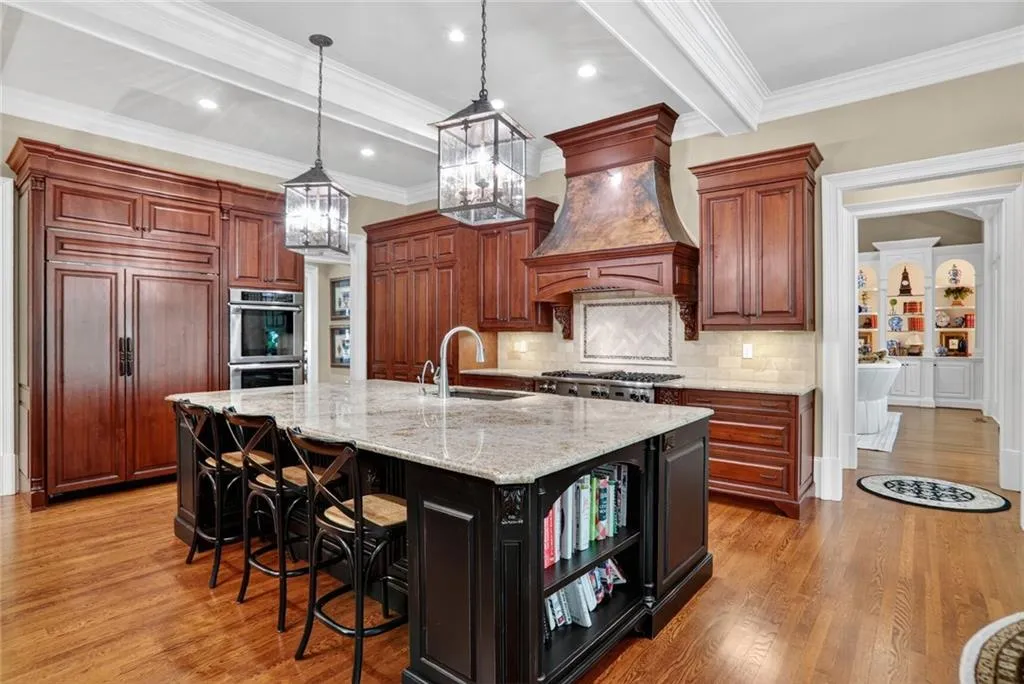Kitchen with decorative light fixtures, a breakfast bar, light stone counters, a large island, and light wood-style floors