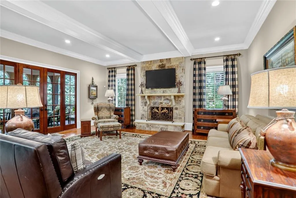 Living area featuring beamed ceiling, crown molding, a fireplace, wood finished floors, and recessed lighting