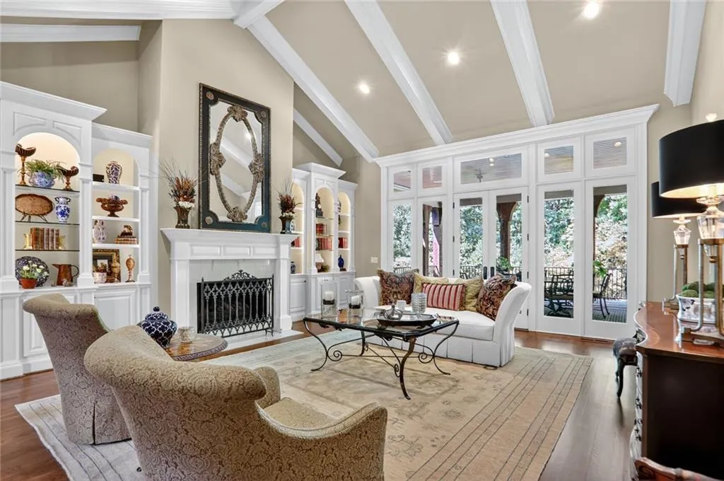 Living area featuring a fireplace with flush hearth, wood finished floors, beam ceiling, high vaulted ceiling, and french doors