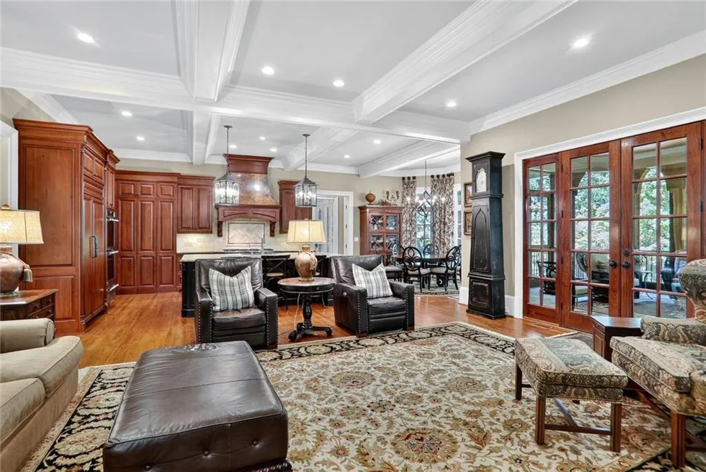 Living room with beam ceiling, light wood-style flooring, french doors, a chandelier, and crown molding
