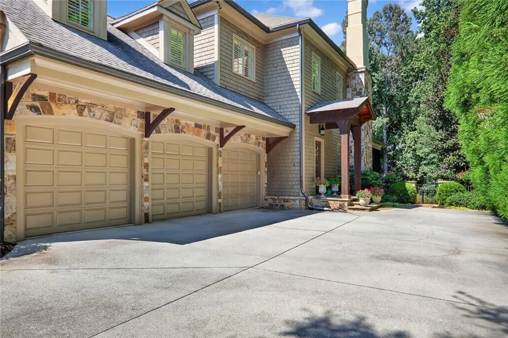 View of side of property with stone siding, concrete driveway, and a chimney