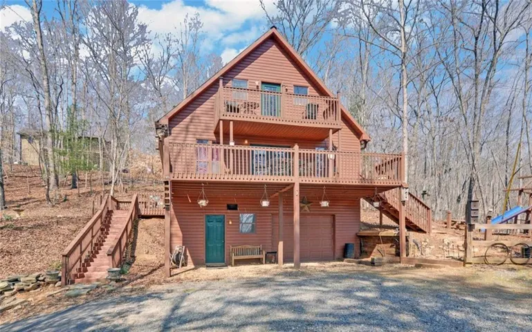 Back of house with a deck, a garage, and gravel driveway