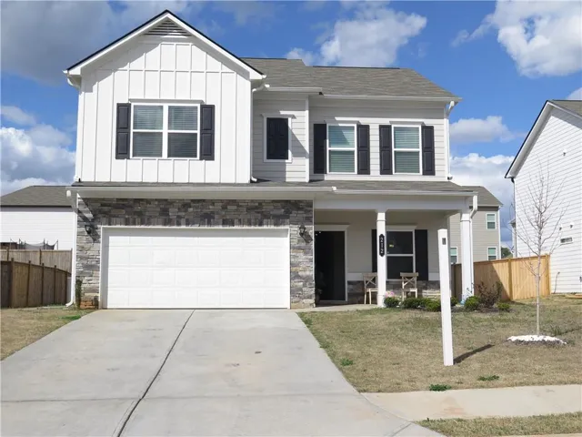 View of front of property featuring board and batten siding, stone siding, an attached garage, and a porch