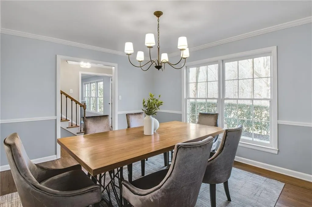 Dining space with crown molding, a notable chandelier, a wealth of natural light, and dark wood-type flooring