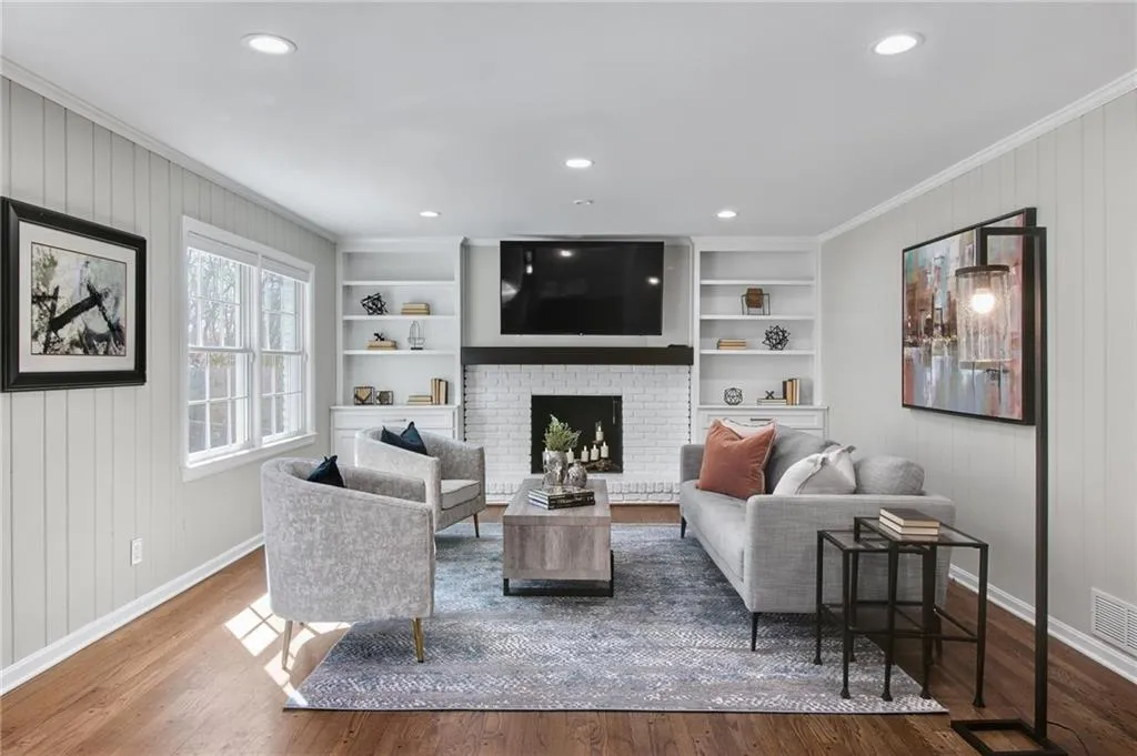 Living room featuring ornamental molding, a fireplace, hardwood / wood-style floors, and built in features