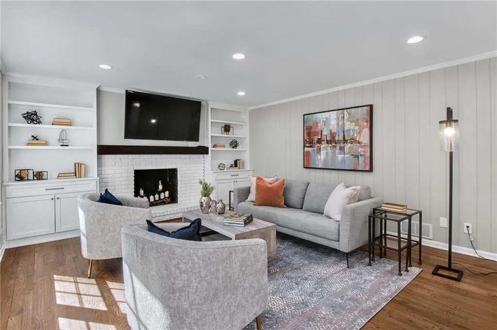 Living room with built in features, ornamental molding, dark hardwood / wood-style floors, and a brick fireplace