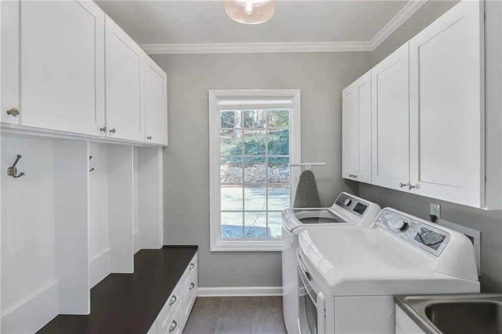 Laundry room featuring cabinets, crown molding, and washing machine and clothes dryer