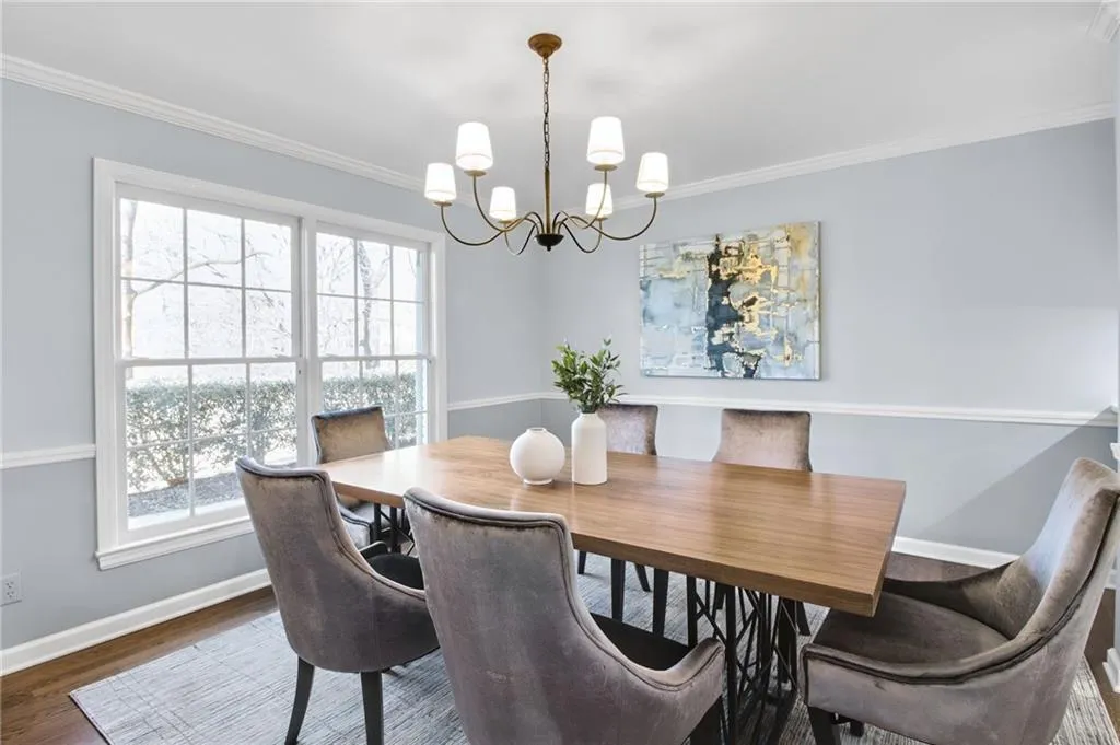 Dining area featuring a notable chandelier, crown molding, and dark wood-type flooring