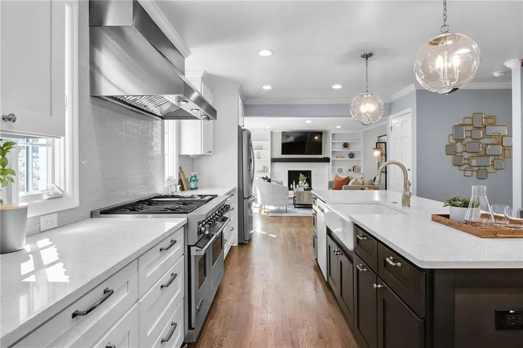 Kitchen with extractor fan, decorative light fixtures, stainless steel appliances, and white cabinets
