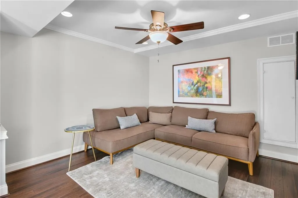 Living room featuring crown molding, dark hardwood / wood-style floors, and ceiling fan