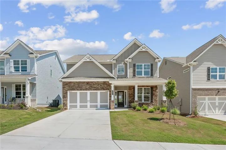 Craftsman-style exterior with stone and siding facade, covered front porch, two-car garage, and concrete driveway