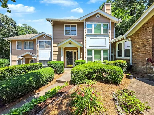 Split-level facade with siding, multiple large windows, covered entryway, and mature landscaping