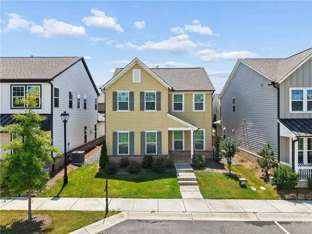 Yellow siding exterior with a covered entry, dark green shutters, and a well-maintained lawn