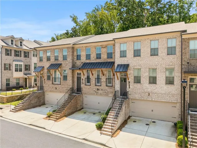 Brick exterior with multiple windows, individual garage access, and covered entryways