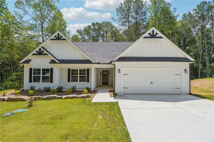 Modern farmhouse featuring roof with shingles, a garage, board and batten siding, and concrete driveway