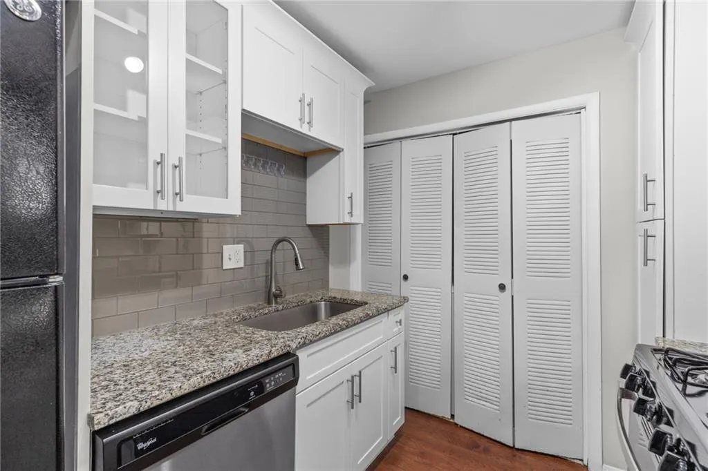 Kitchen featuring glass insert cabinets, backsplash, dishwasher, white cabinets, and gas range
