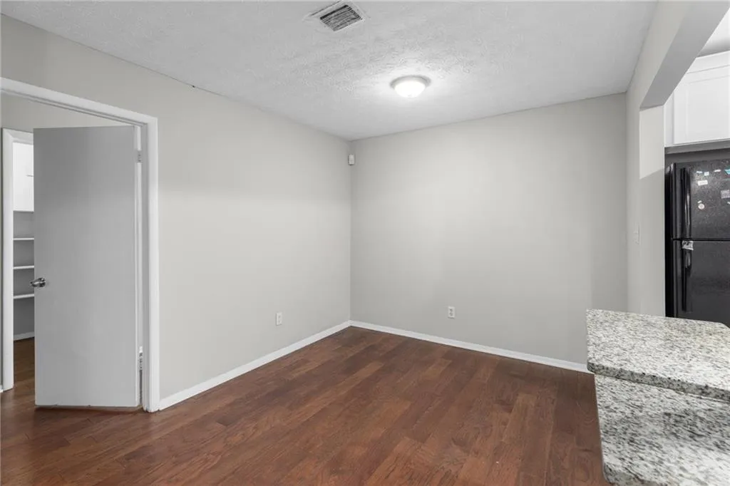 Unfurnished dining area with a textured ceiling and dark wood-style floors