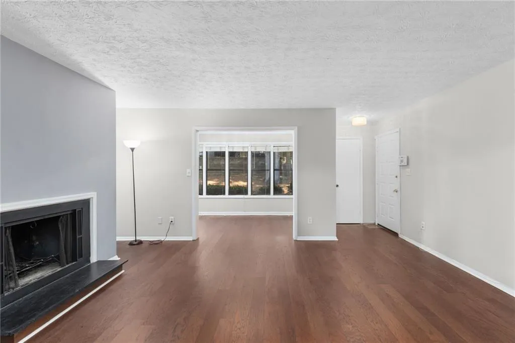 Unfurnished living room featuring dark wood-style floors, a fireplace with raised hearth, and a textured ceiling