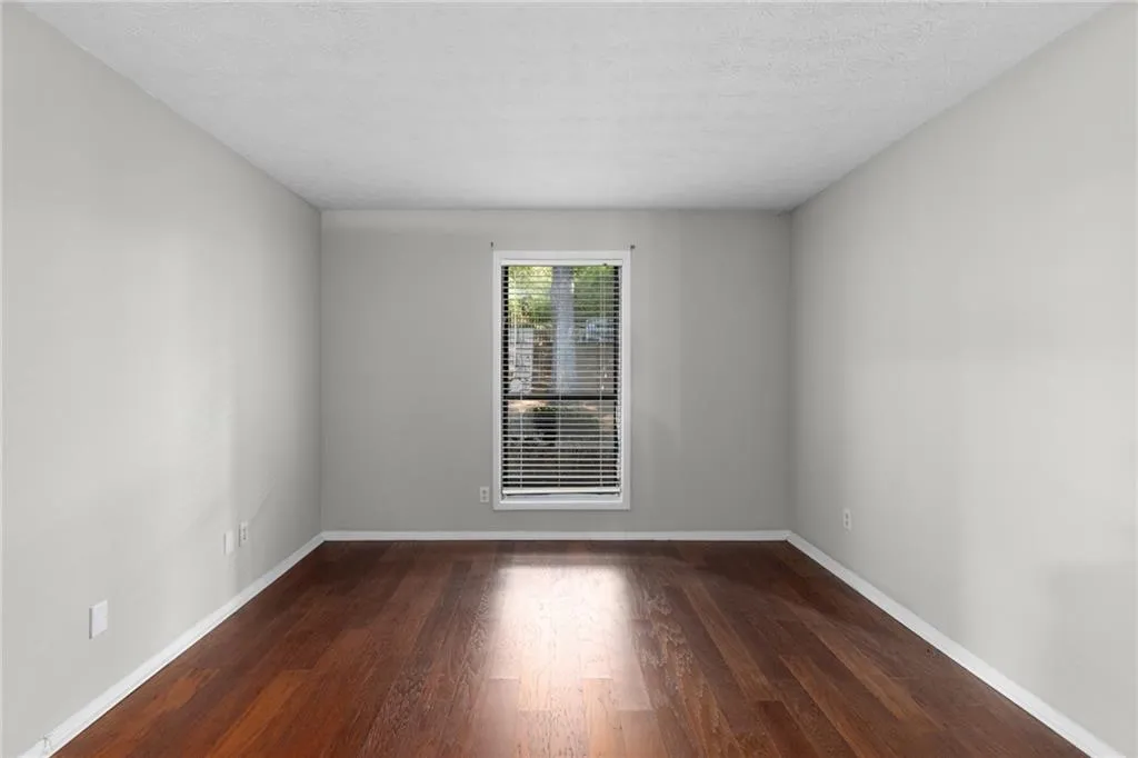 Empty room featuring dark wood-style flooring and a textured ceiling