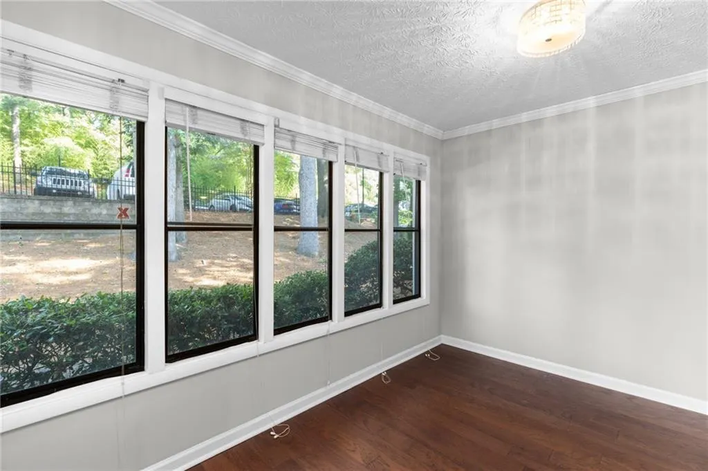Spare room featuring dark wood-style flooring, a textured ceiling, and crown molding