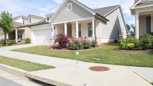 Siding and brick exterior with a columned front porch, a two-car garage, and established landscaping