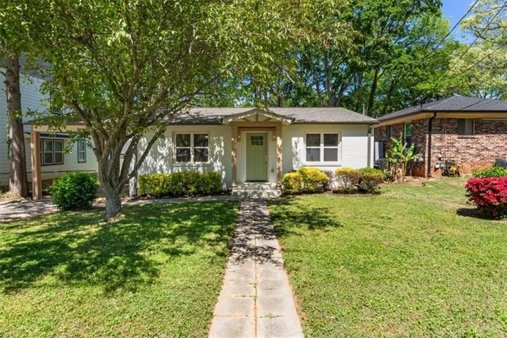 The property features a well-maintained lawn with a stone pathway leading to the entrance