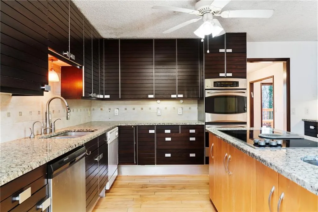 Kitchen with light wood finished floors, stainless steel appliances, decorative backsplash, a sink, and a textured ceiling