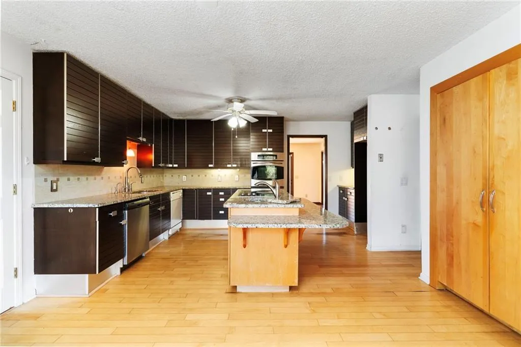 Kitchen with appliances with stainless steel finishes, a sink, an island with sink, light wood-type flooring, and a kitchen bar