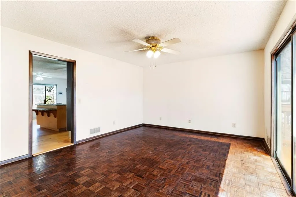 Empty room with baseboards, visible vents, ceiling fan, and a textured ceiling