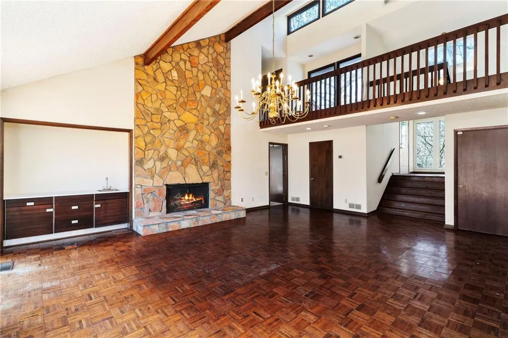 Unfurnished living room with stairs, a fireplace, beam ceiling, and a healthy amount of sunlight