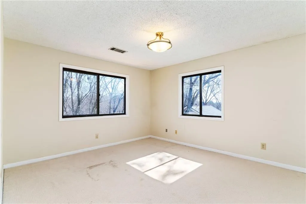 Unfurnished room with a textured ceiling, carpet, visible vents, and baseboards