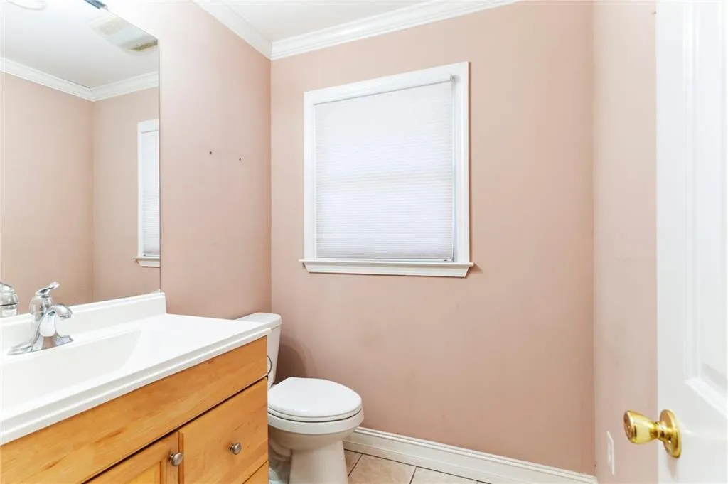 Bathroom with visible vents, toilet, tile patterned flooring, crown molding, and vanity