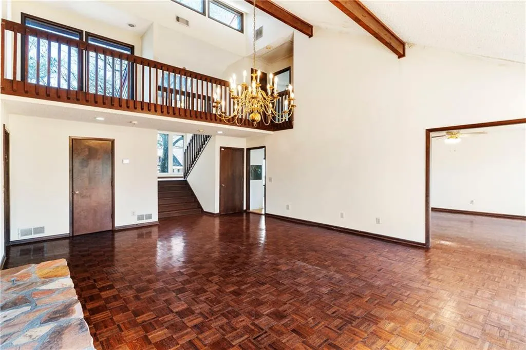 Unfurnished living room featuring high vaulted ceiling, beamed ceiling, and visible vents