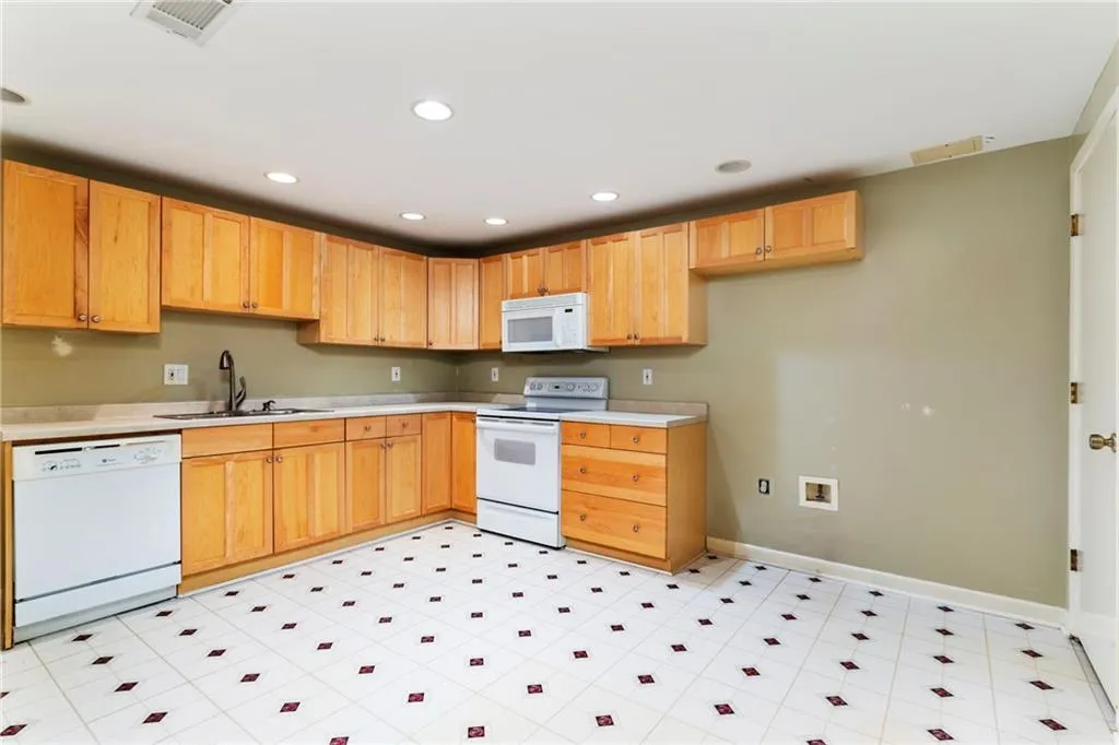 Kitchen featuring light countertops, white appliances, visible vents, and a sink