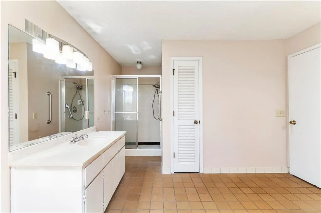 Full bathroom featuring a closet, tile patterned flooring, a shower stall, and vanity