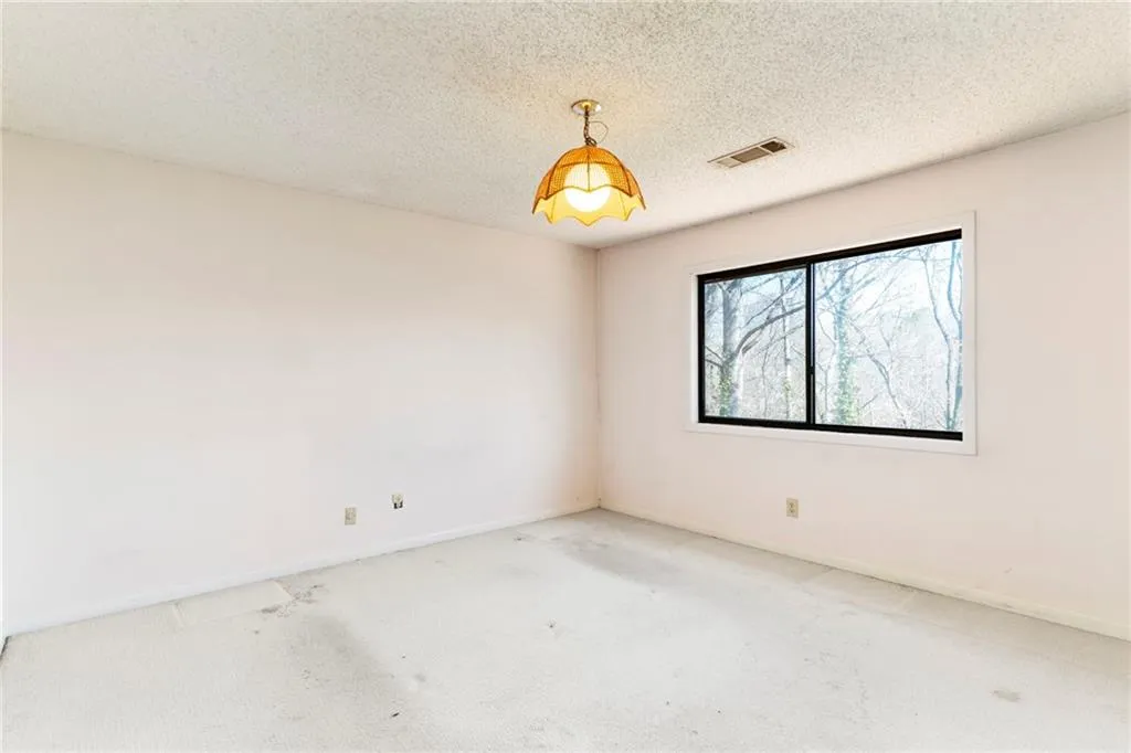 Spare room featuring baseboards, visible vents, a textured ceiling, and carpet flooring
