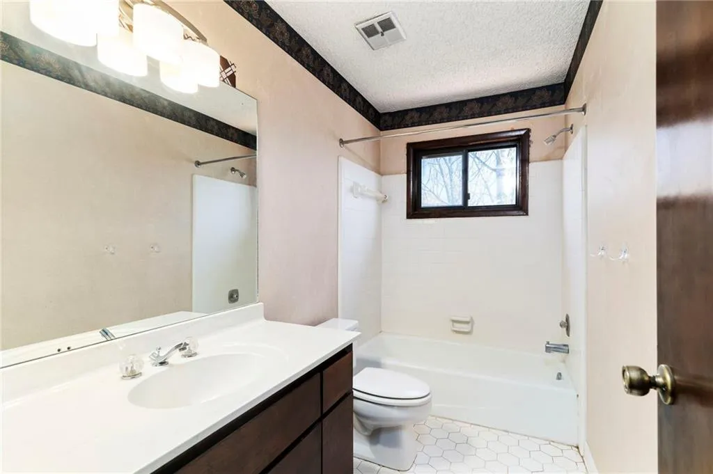 Bathroom with visible vents, toilet, shower / bathtub combination, a textured ceiling, and vanity