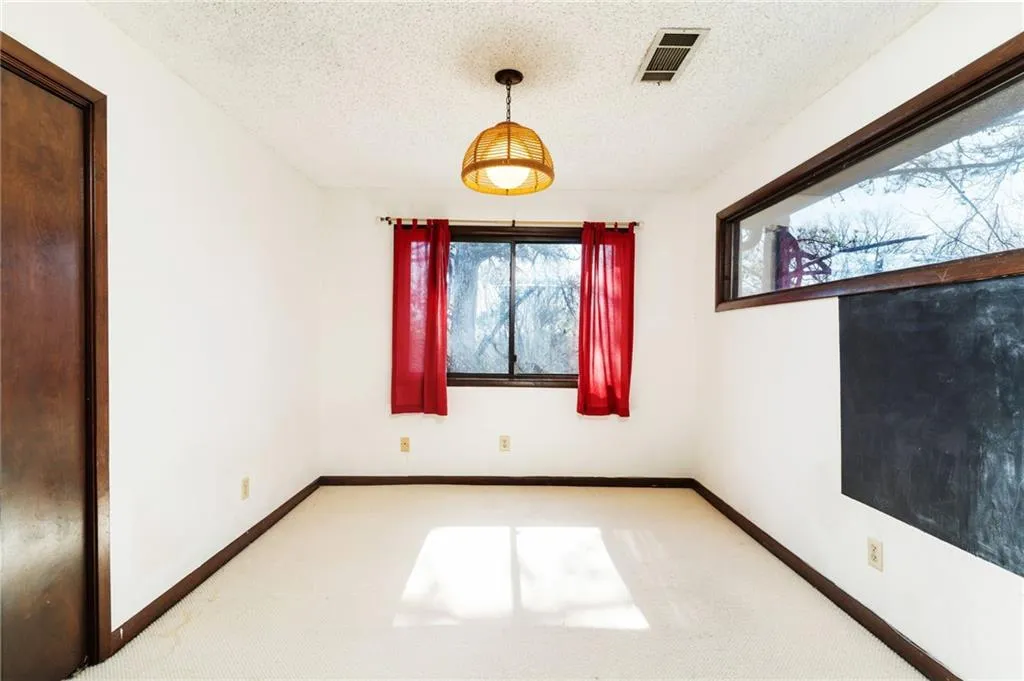 Carpeted spare room featuring baseboards, visible vents, and a textured ceiling