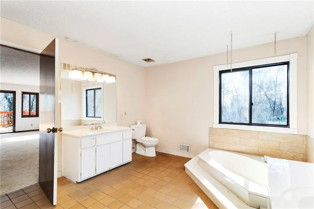 Full bath with a textured ceiling, a garden tub, toilet, vanity, and visible vents