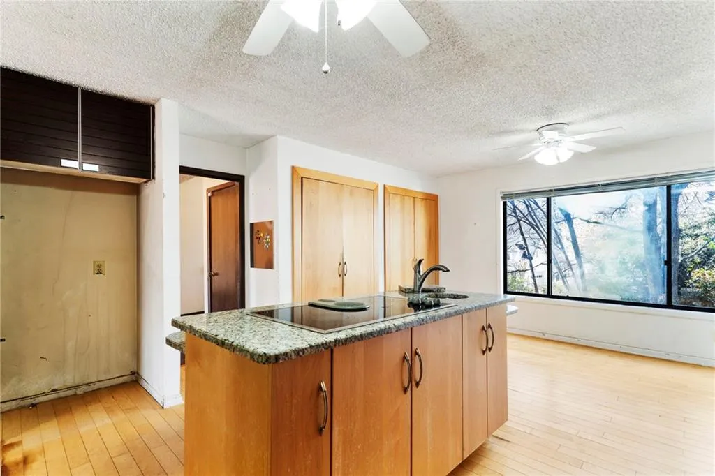 Kitchen featuring a kitchen island with sink, ceiling fan, a sink, light wood-type flooring, and black electric cooktop
