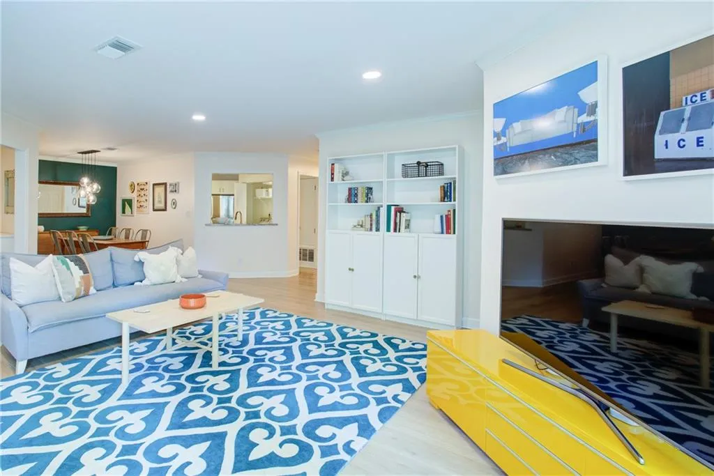 Living area with wood finished floors, ornamental molding, a chandelier, and recessed lighting