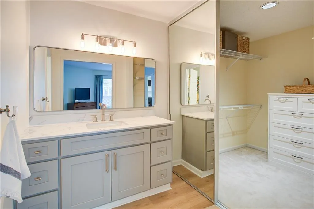 Bathroom featuring two vanities, wood finished floors, and recessed lighting